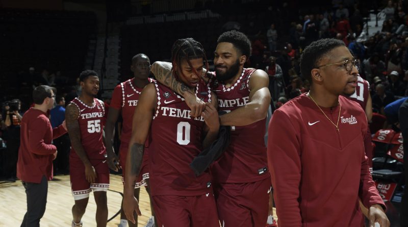 Damian Dunn embraces Khalif Battle surrounded by their teammates, celebrating the win over Rutgers and Battle's impressive performance.